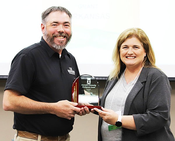 Brad McGinley, County Extension Agent-Agriculture at University of Arkansas, accepts an award from Tandee White, Community Development Program Manager with Entergy Arkansas, serving as Vice President of Programs for ACDS.