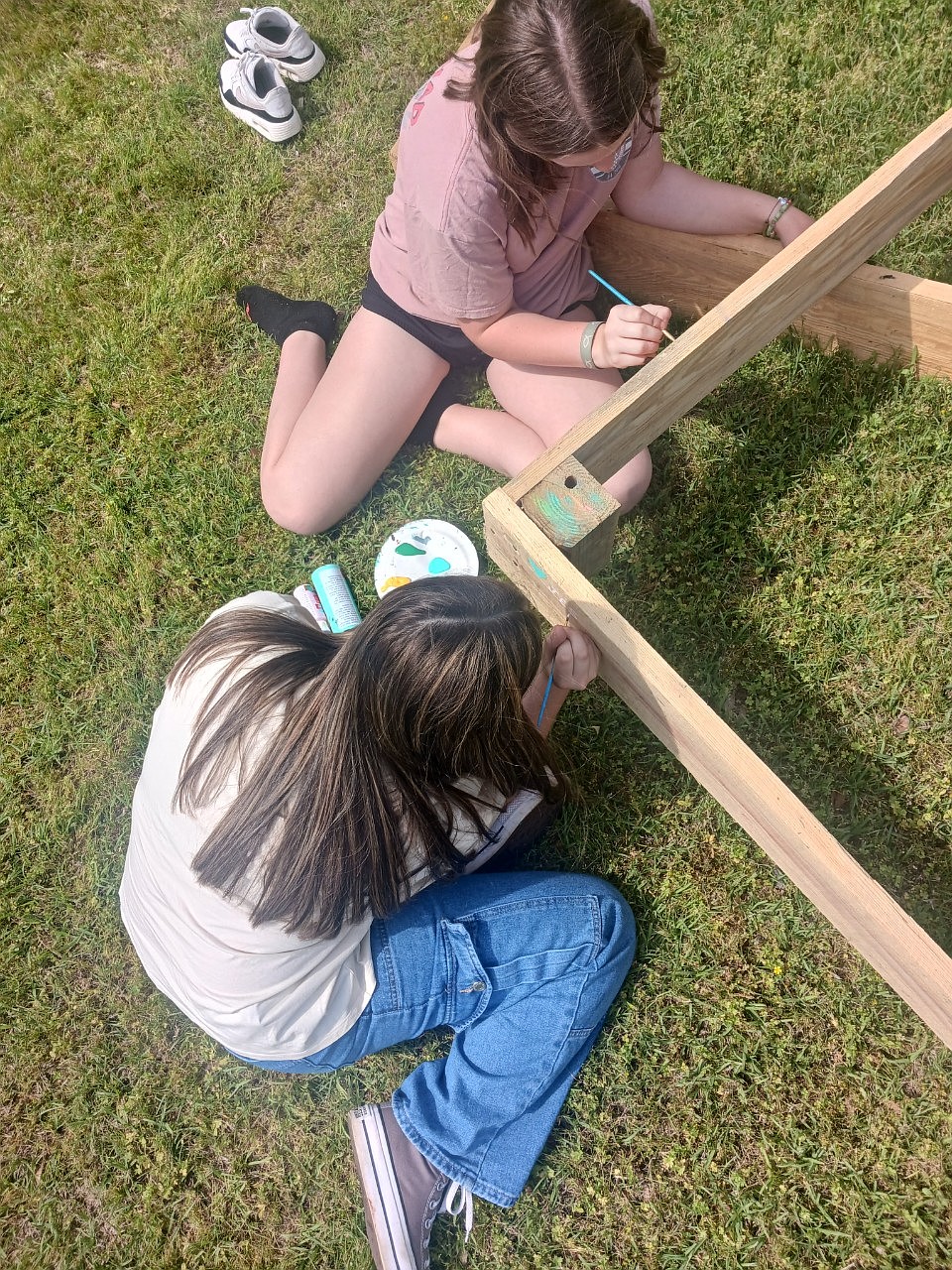 Two students work on  frame for plants that will be part of a garden they are creating.