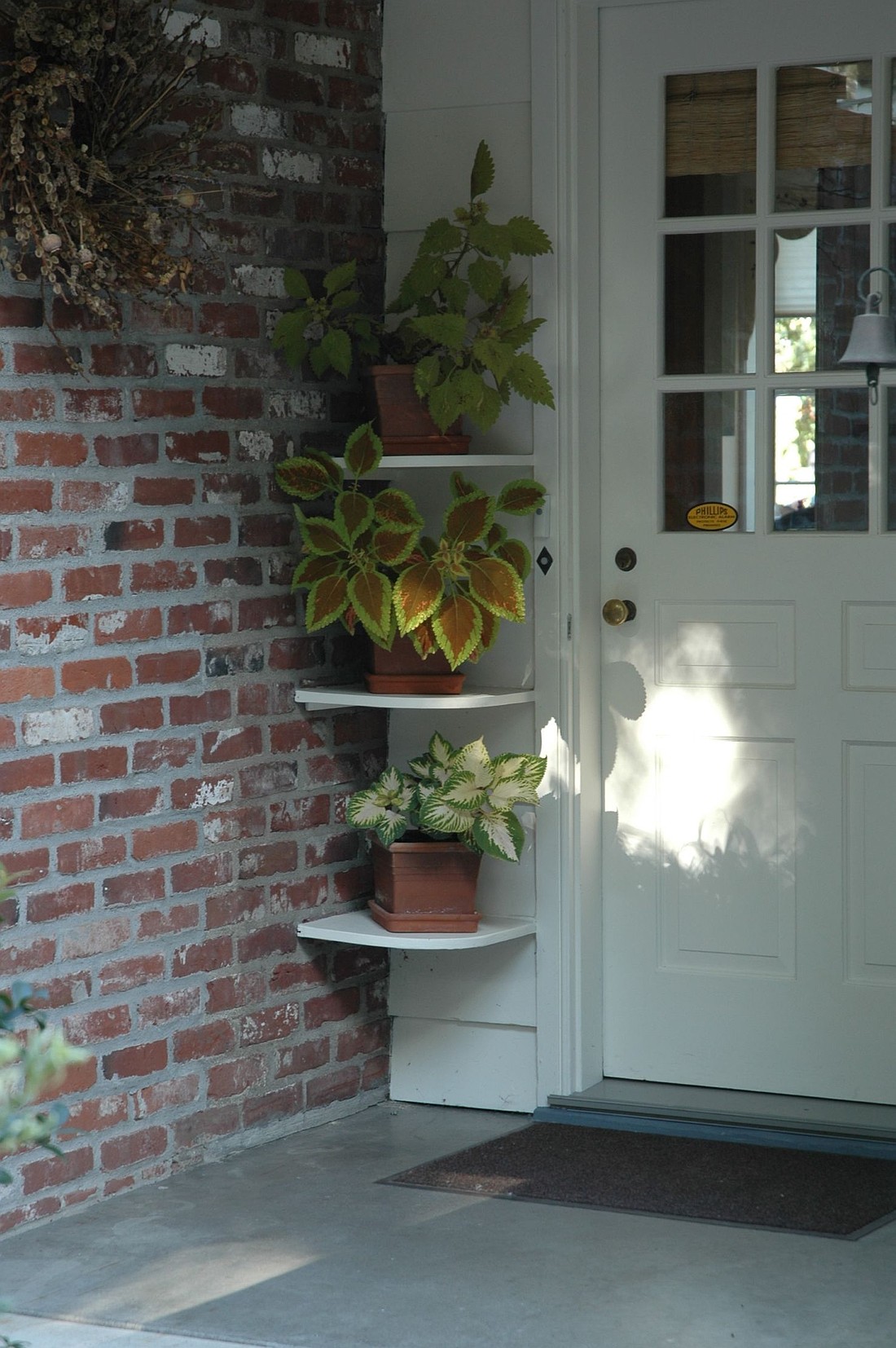 Corner shelves adorned with plants dress up this home’s front porch. (Photo: Courtesy of MelindaMyers.com)