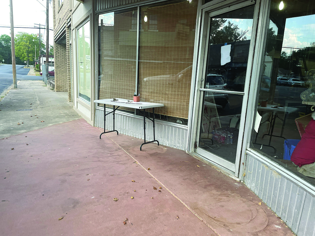 Brody Channell is gathering signatures on a petition against a proposed data center and solar farm. The petition is on a table in front of his building on Oak Street. (Photo: Gretchen Ritchey)