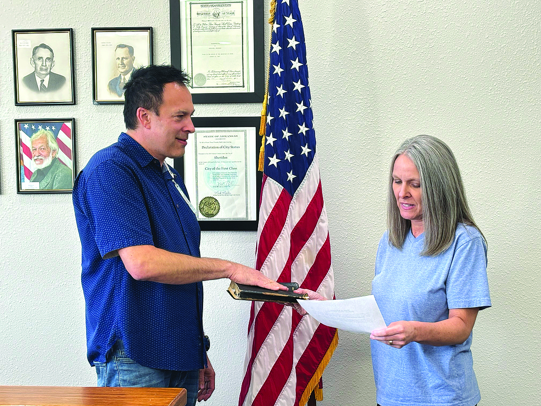 Sheridan Clerk/Treasurer Carrie Smith swears in Justin Wise to the Ward 3 Position 2 seat last week after he was appointed to fill the vacant position. A color photo of Wise’s father, former mayor Joe Wise, can be seen hanging on the wall. (Photo By Gretchen Ritchey)