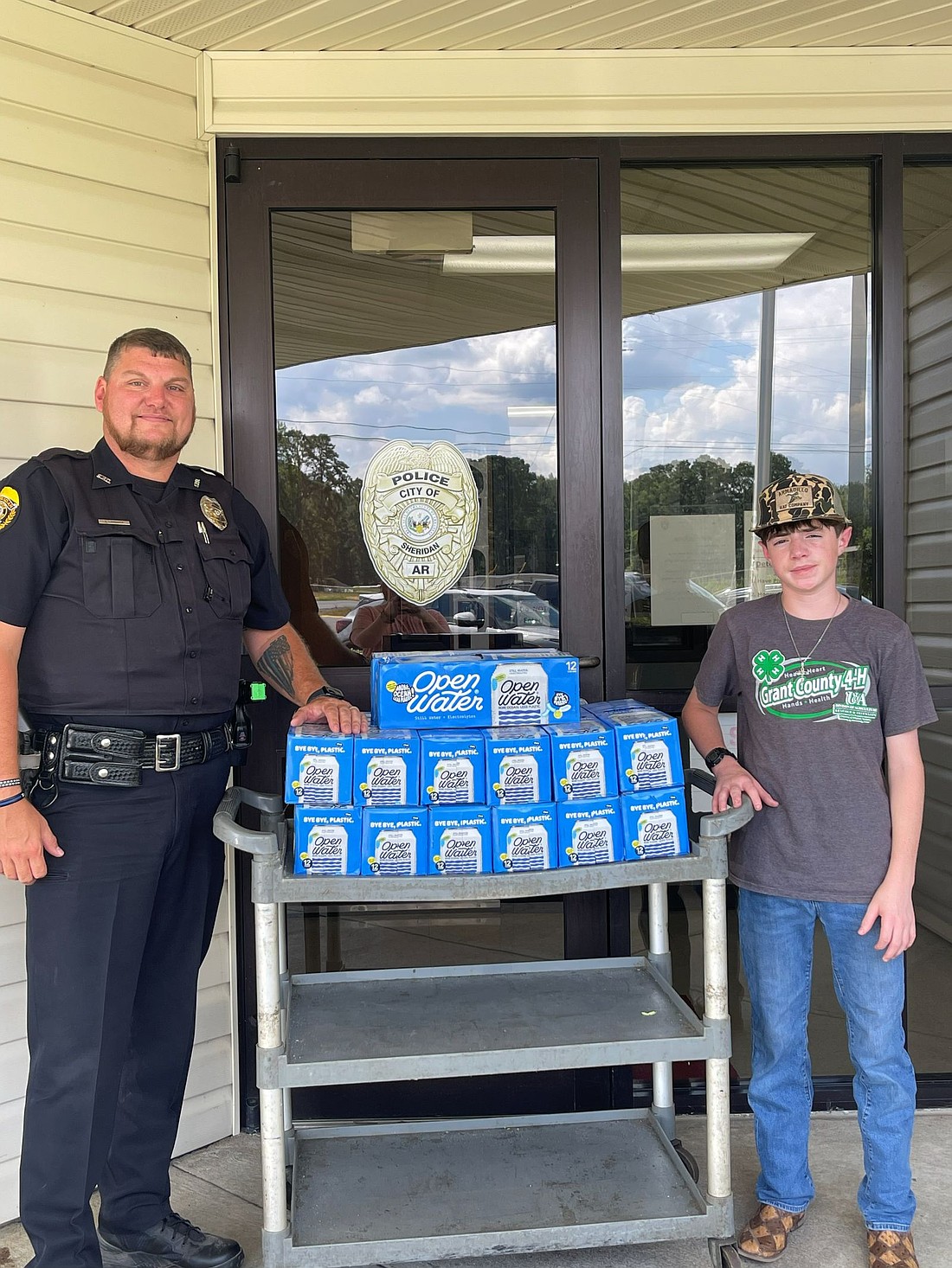 Sheridan Police Officer Daniel Laminack poses with Preston Bazare, 14, a member of Grant County 4-H who gathered more than 500 cases of water through community donations and delivered them to the Sheridan sheriff’s, police, fire and EMS departments multiple times throughout this summer. (Division of Agriculture photo.)